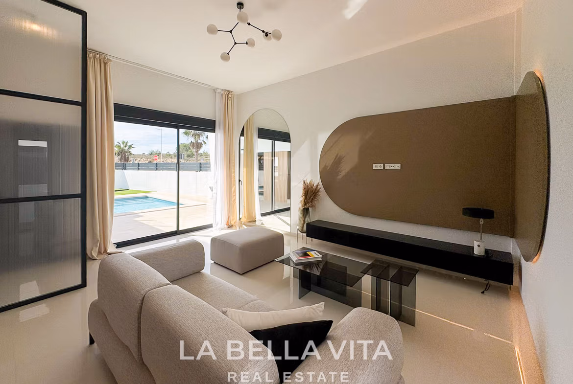 Bright, modern living room with plush sofa and glass sliding doors opening to a private pool in San Miguel de Salinas villa.