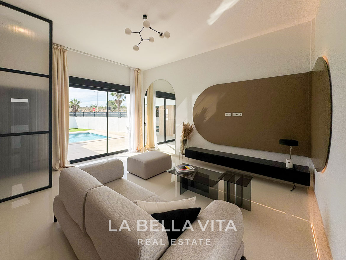 Bright, modern living room with plush sofa and glass sliding doors opening to a private pool in San Miguel de Salinas villa.