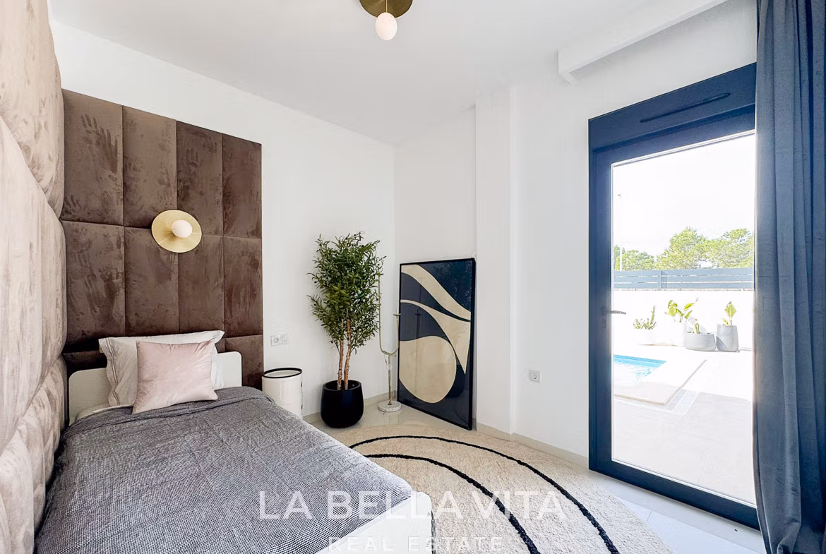 Bright modern bedroom with plush headboard, elegant decor, and sliding door opening to private pool in San Miguel de Salinas villa.