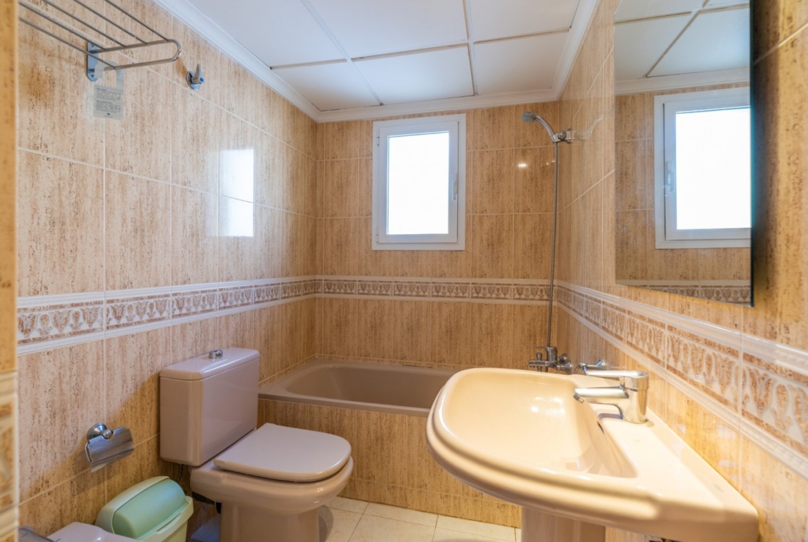 Compact, sunlit bathroom with classic fixtures and tiled walls in top floor bungalow apartments in Calpe