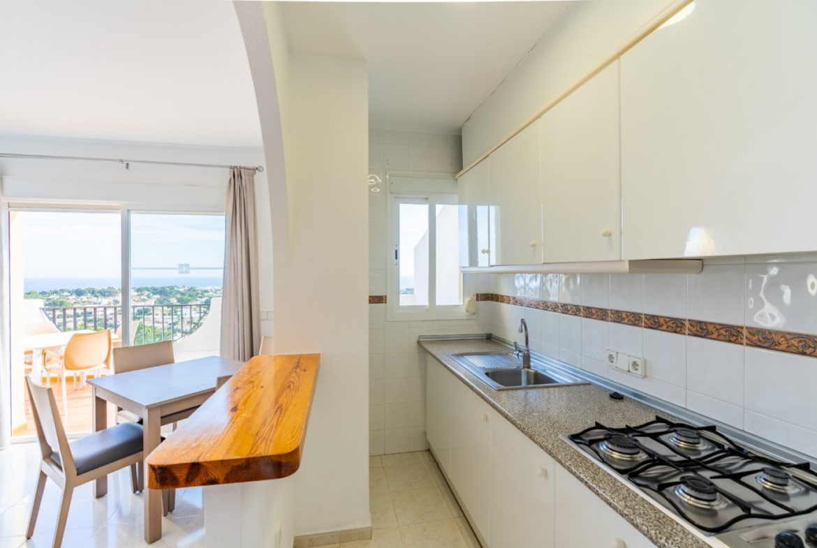 Bright modern kitchen and dining area with sunny terrace and panoramic sea view in top floor bungalow apartment in Calpe.