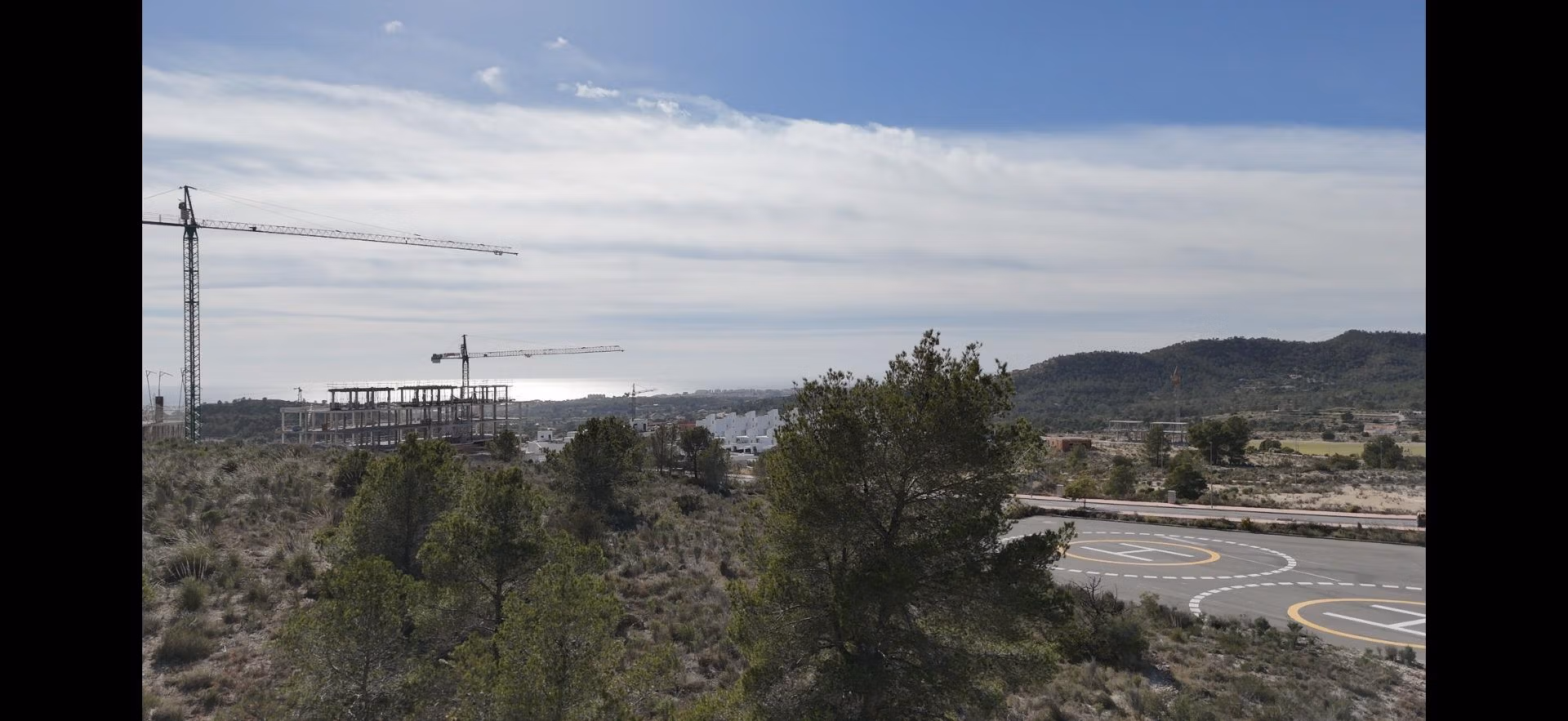 Tourist-Licensed-New-Build-Apartments-in-Finestrat-Investment-Opportunity-Near-Golf-and-Benidorm-11 Panoramic view of landscaped hills and construction cranes near new 1-bedroom tourist licensed apartment in Finestrat, Benidorm