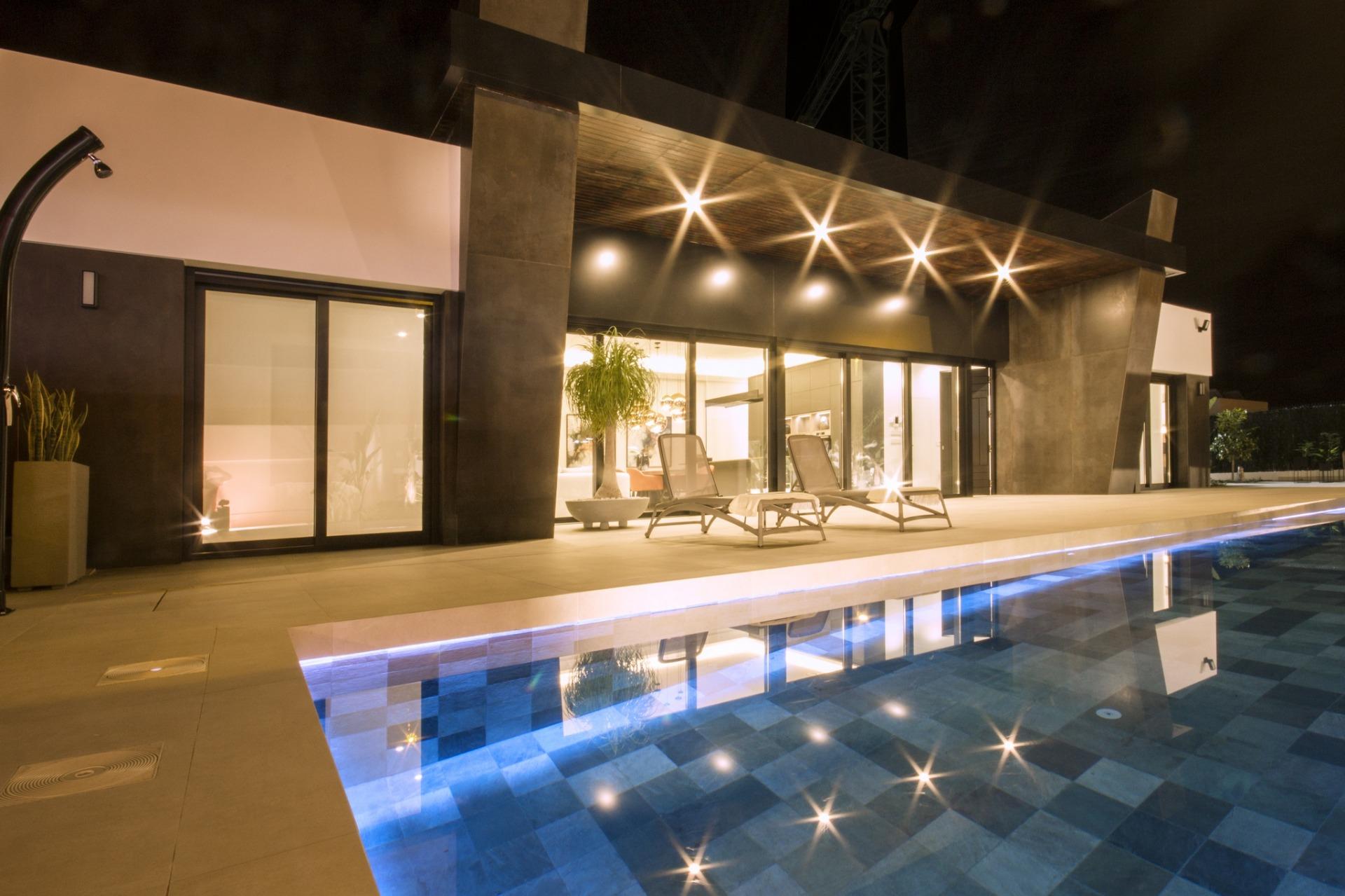 Luxurious modern 3-bedroom villa terrace with sleek sun loungers and illuminated private pool at night in Ciudad Quesada,...