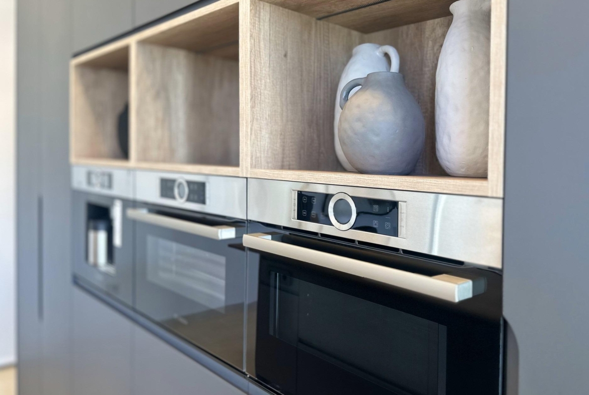 Sleek modern kitchen in bespoke Ciudad Quesada villa with built-in stainless steel ovens and natural wood open shelving...