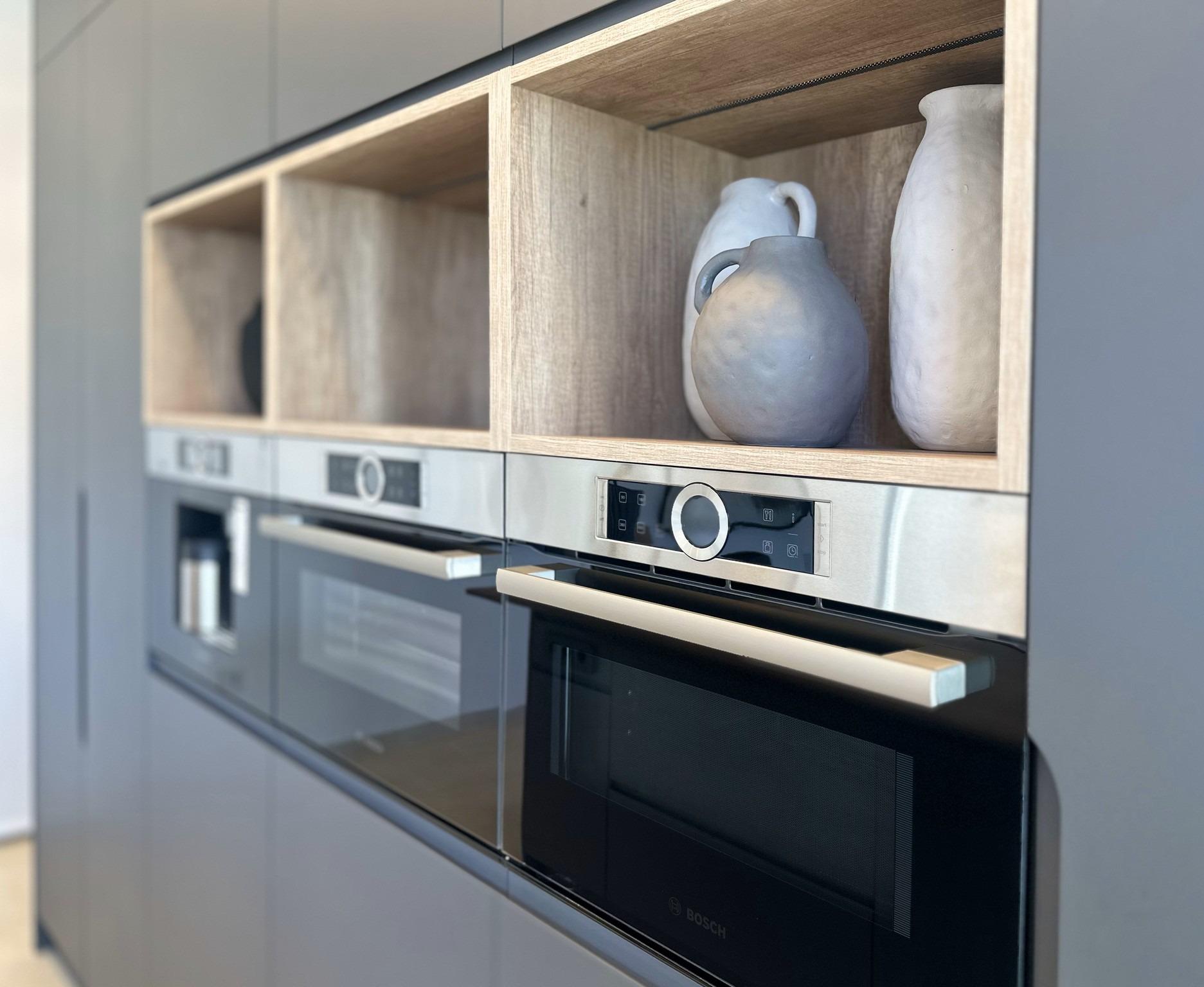 Sleek modern kitchen in bespoke Ciudad Quesada villa with built-in stainless steel ovens and natural wood open shelving...