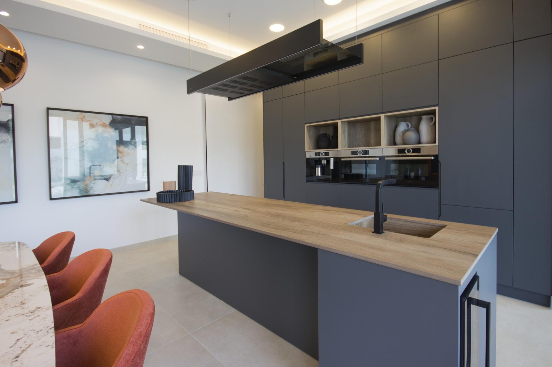 Sleek modern kitchen in bespoke 3 bedroom villa in Ciudad Quesada featuring matte grey cabinetry and natural wood island...