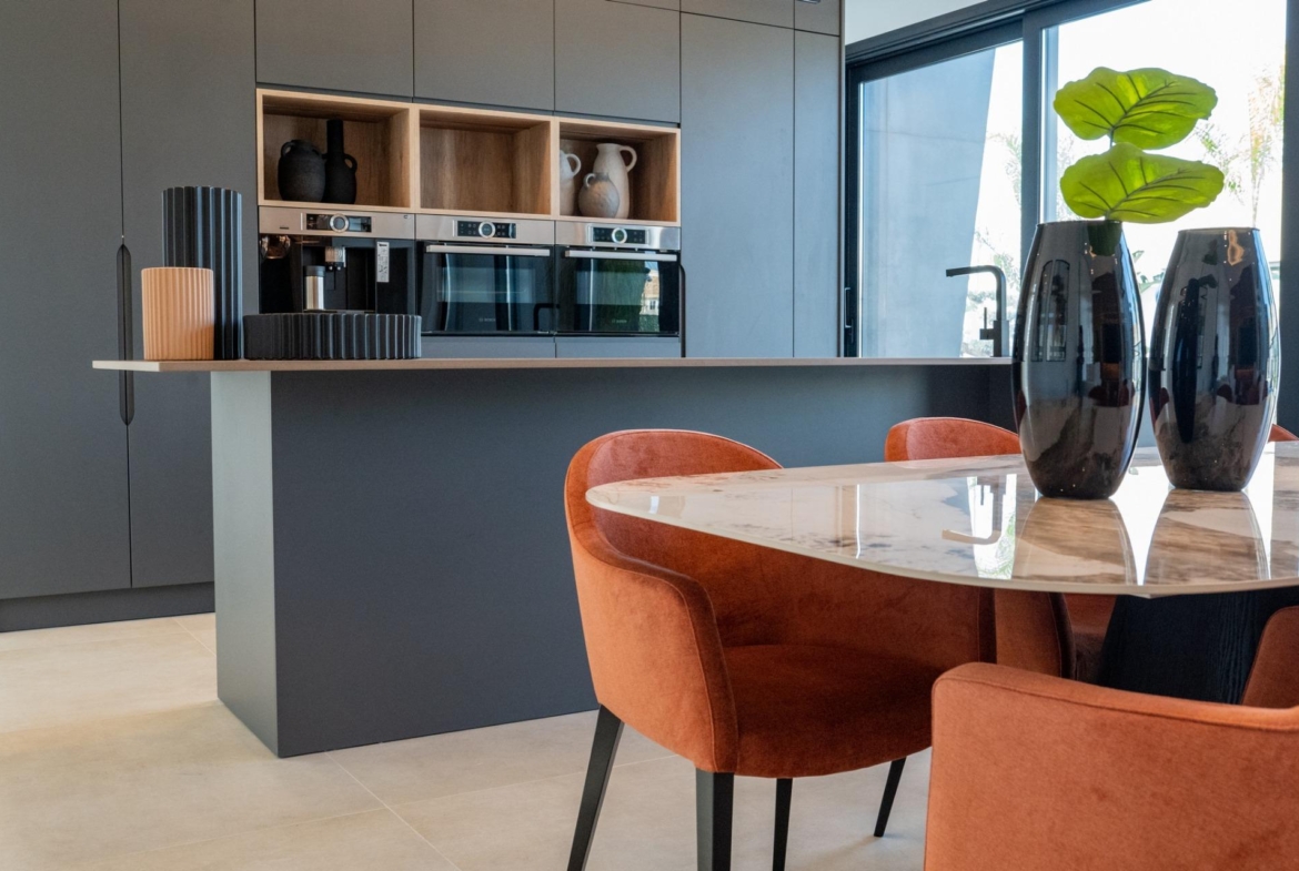 Sleek modern kitchen in new build 3-bedroom villa in Ciudad Quesada with elegant marble dining table and warm terracotta...