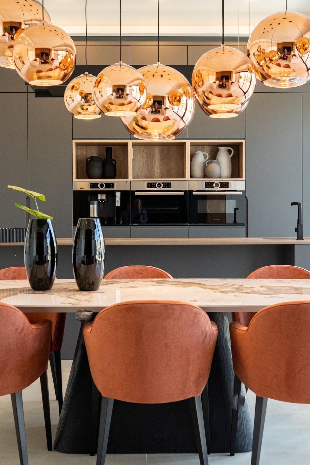 Modern bespoke kitchen in Ciudad Quesada villa featuring sleek cabinetry, polished marble table, and warm copper pendant...