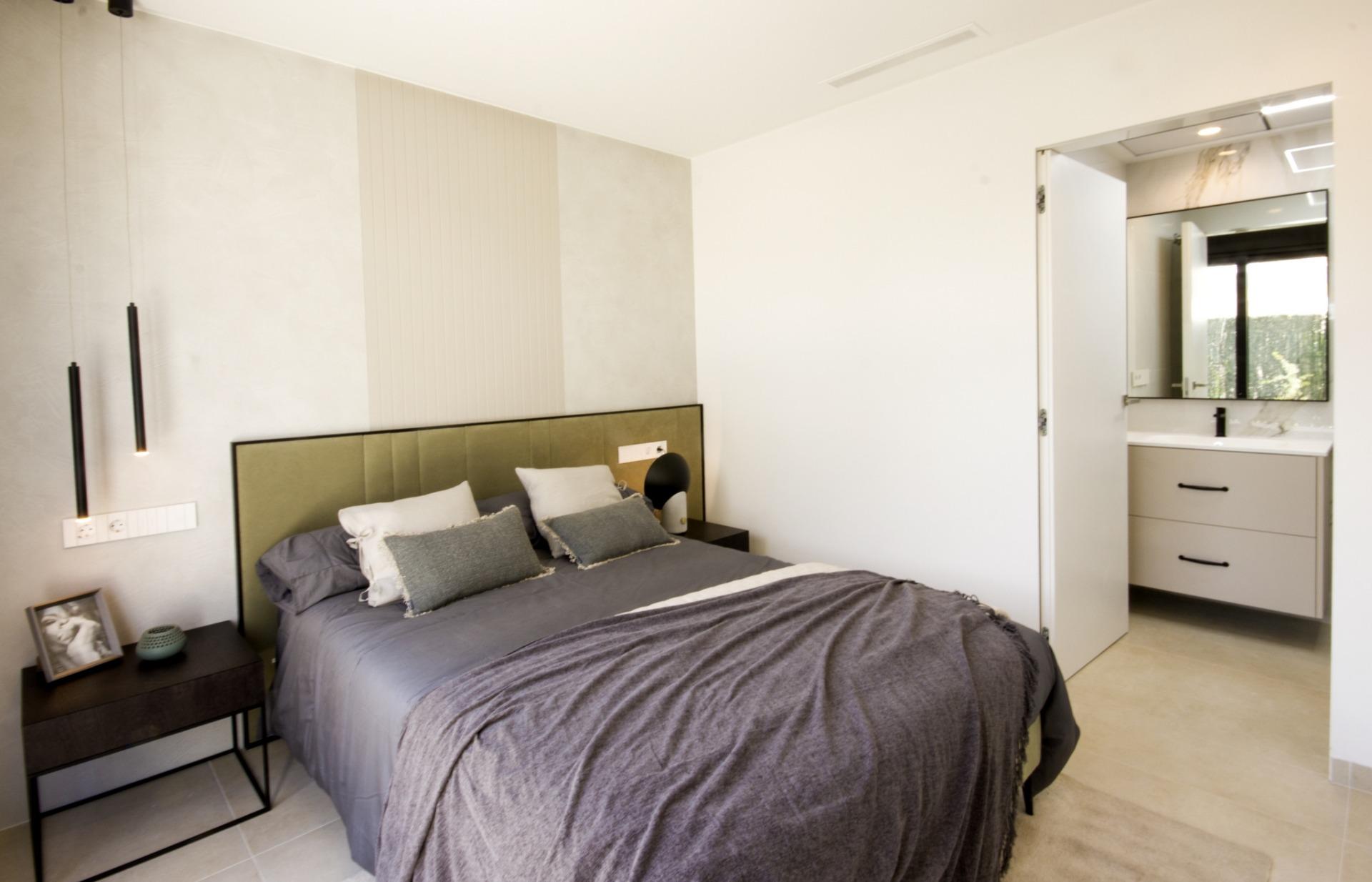 Bright modern bedroom in bespoke 3-bedroom villa in Ciudad Quesada with elegant green upholstered headboard and sleek...