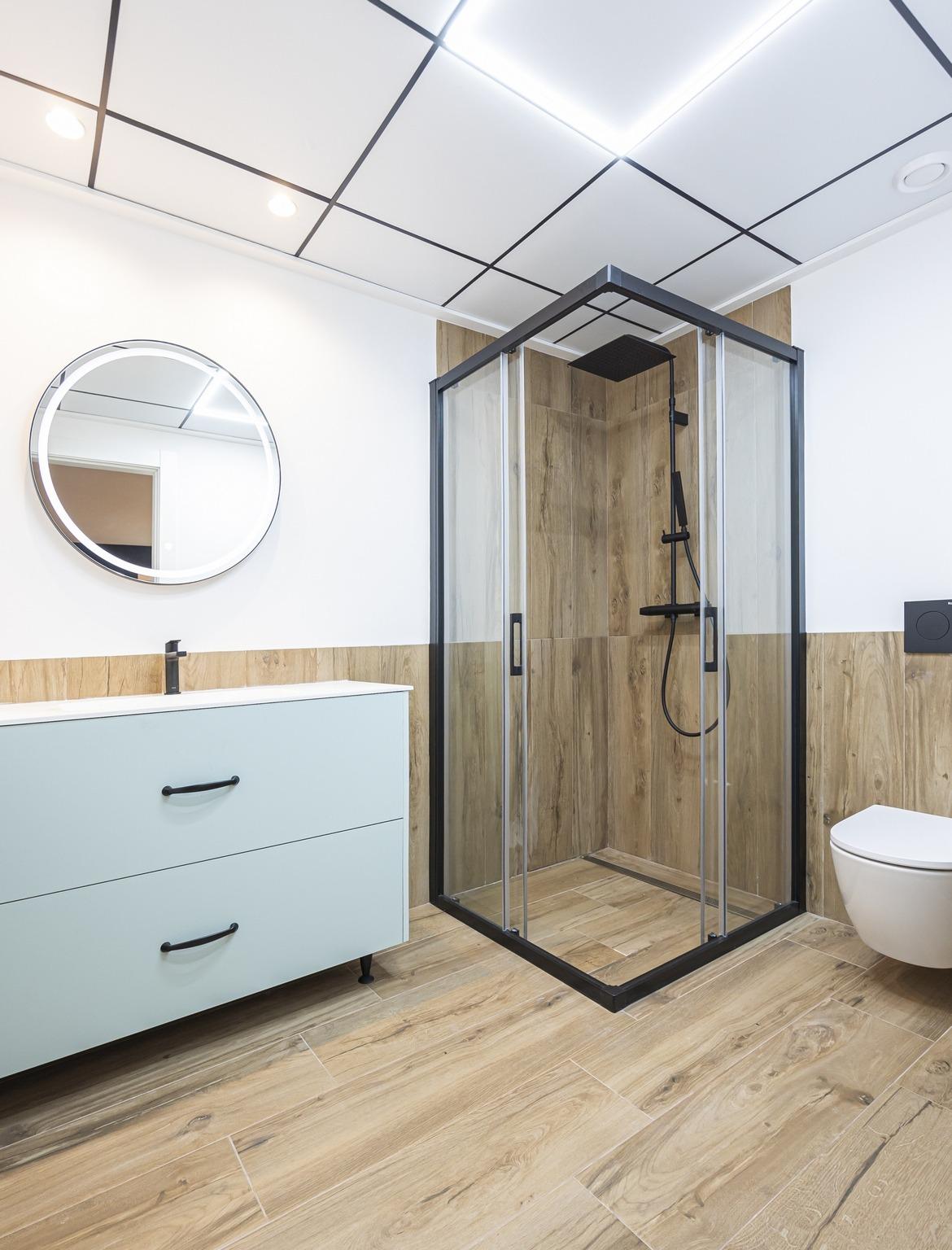Modern bathroom with sleek black-framed shower and wood-effect tiles in bespoke 3-bedroom villa in Ciudad Quesada, Costa...