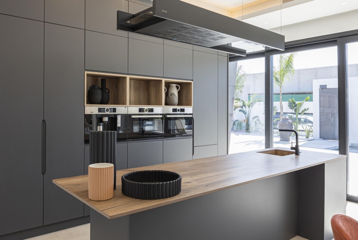 Sleek modern kitchen in bespoke 3-bedroom villa in Ciudad Quesada with matte grey cabinetry, wooden island, and large...