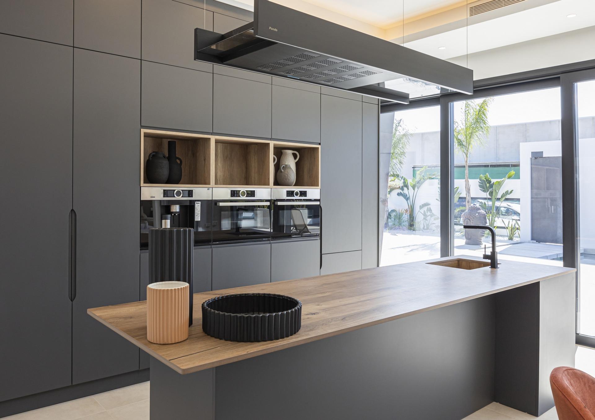 Sleek modern kitchen in bespoke 3-bedroom villa in Ciudad Quesada with matte grey cabinetry, wooden island, and large...