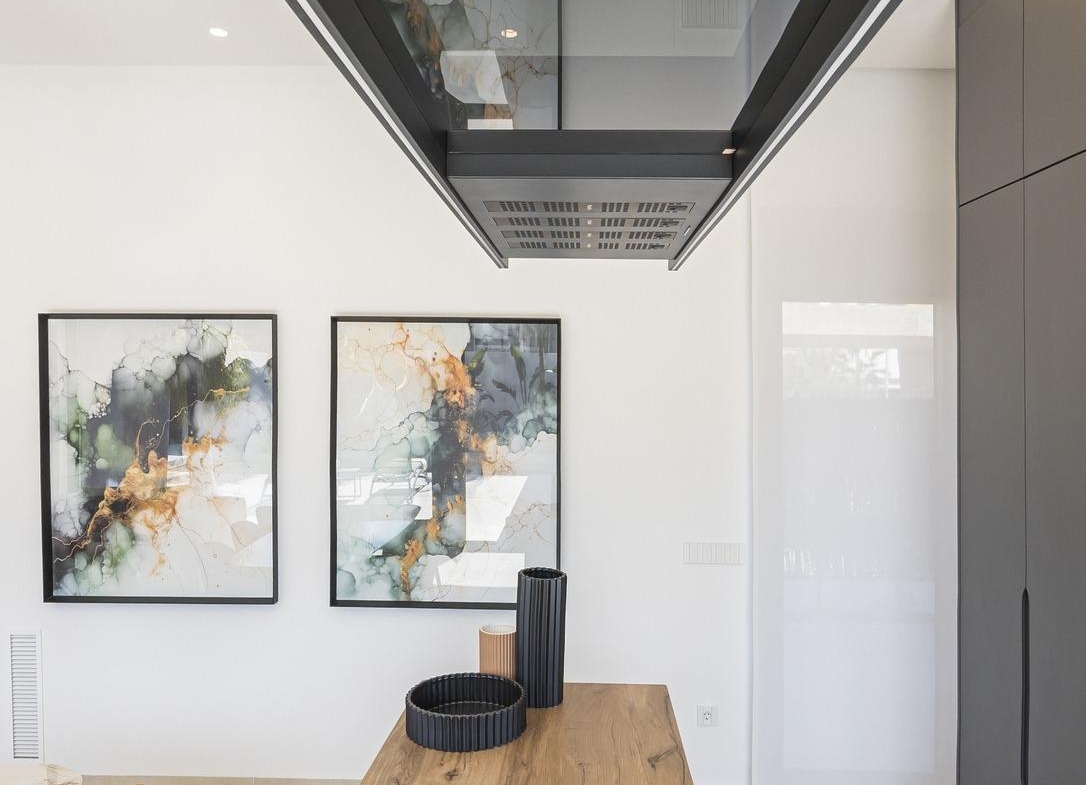 Modern kitchen in bespoke Ciudad Quesada villa featuring sleek black hood, natural wood island, and abstract wall art