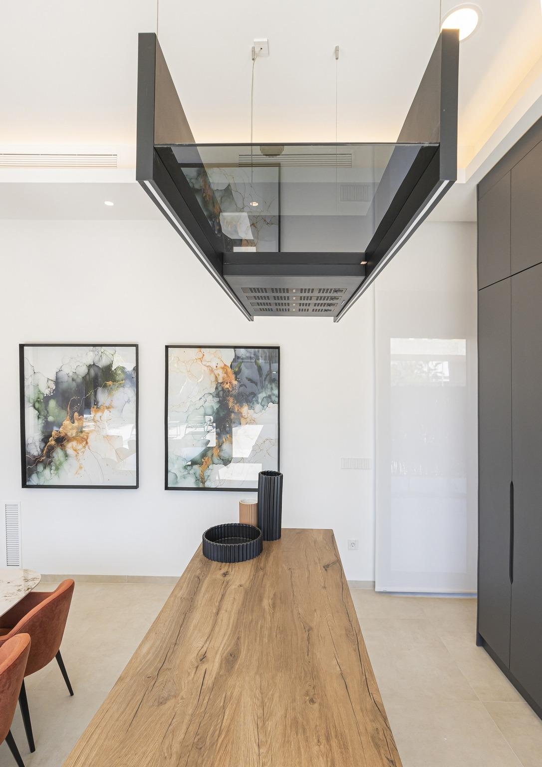 Modern kitchen in bespoke Ciudad Quesada villa featuring sleek black hood, natural wood island, and abstract wall art