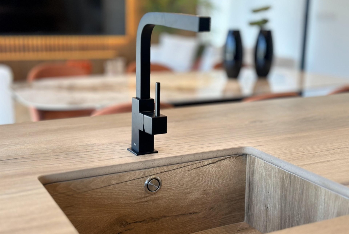 Sleek modern black kitchen faucet set against a warm wood countertop in a bespoke villa kitchen in Ciudad Quesada, Costa...