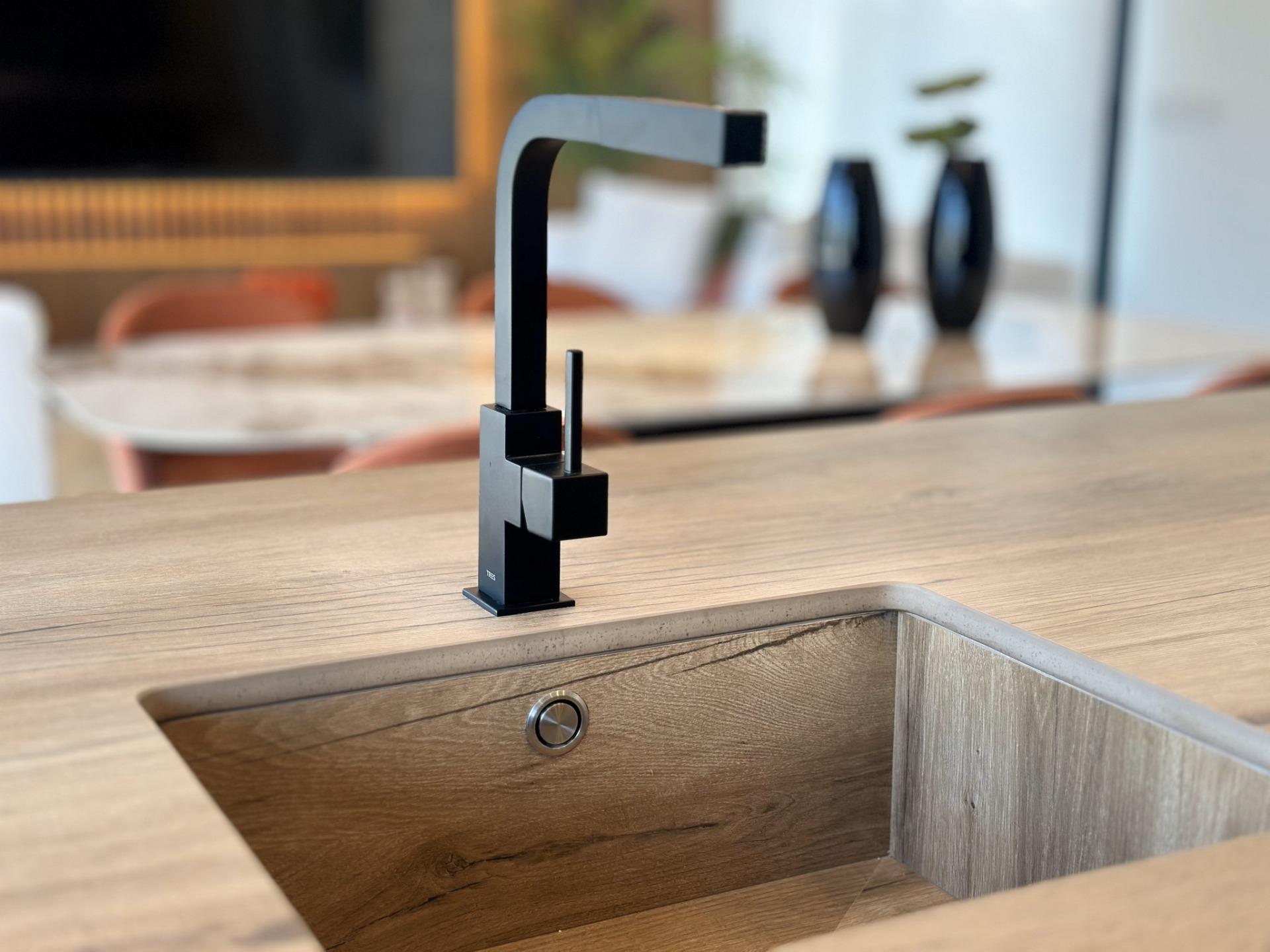 Sleek modern black kitchen faucet set against a warm wood countertop in a bespoke villa kitchen in Ciudad Quesada, Costa...