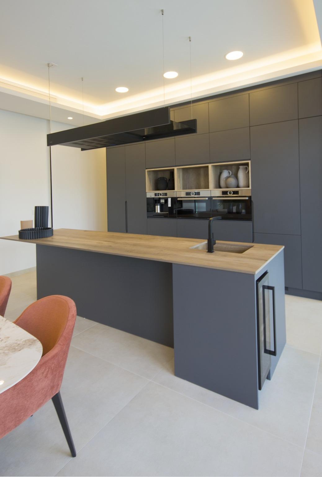 Sleek modern kitchen in bespoke 3-bedroom villa in Ciudad Quesada, featuring matte gray cabinetry and warm wood island...