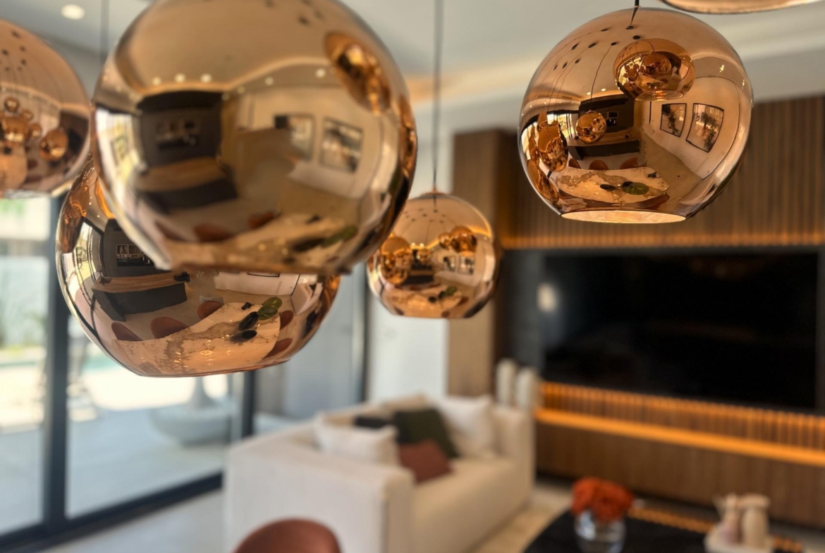 Sleek copper pendant lights reflecting the bright, modern living room of a bespoke 3-bedroom villa in Ciudad Quesada,...
