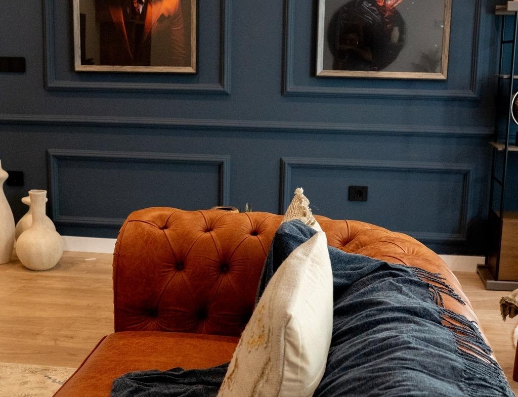 Luxurious living room in bespoke Ciudad Quesada villa with rich navy blue walls, elegant leather sofa, and striking...