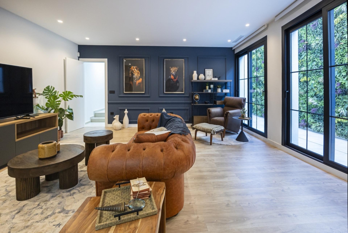 Spacious modern living room in bespoke 3-bedroom villa with leather sofa, artistic decor, and large black-framed windows...