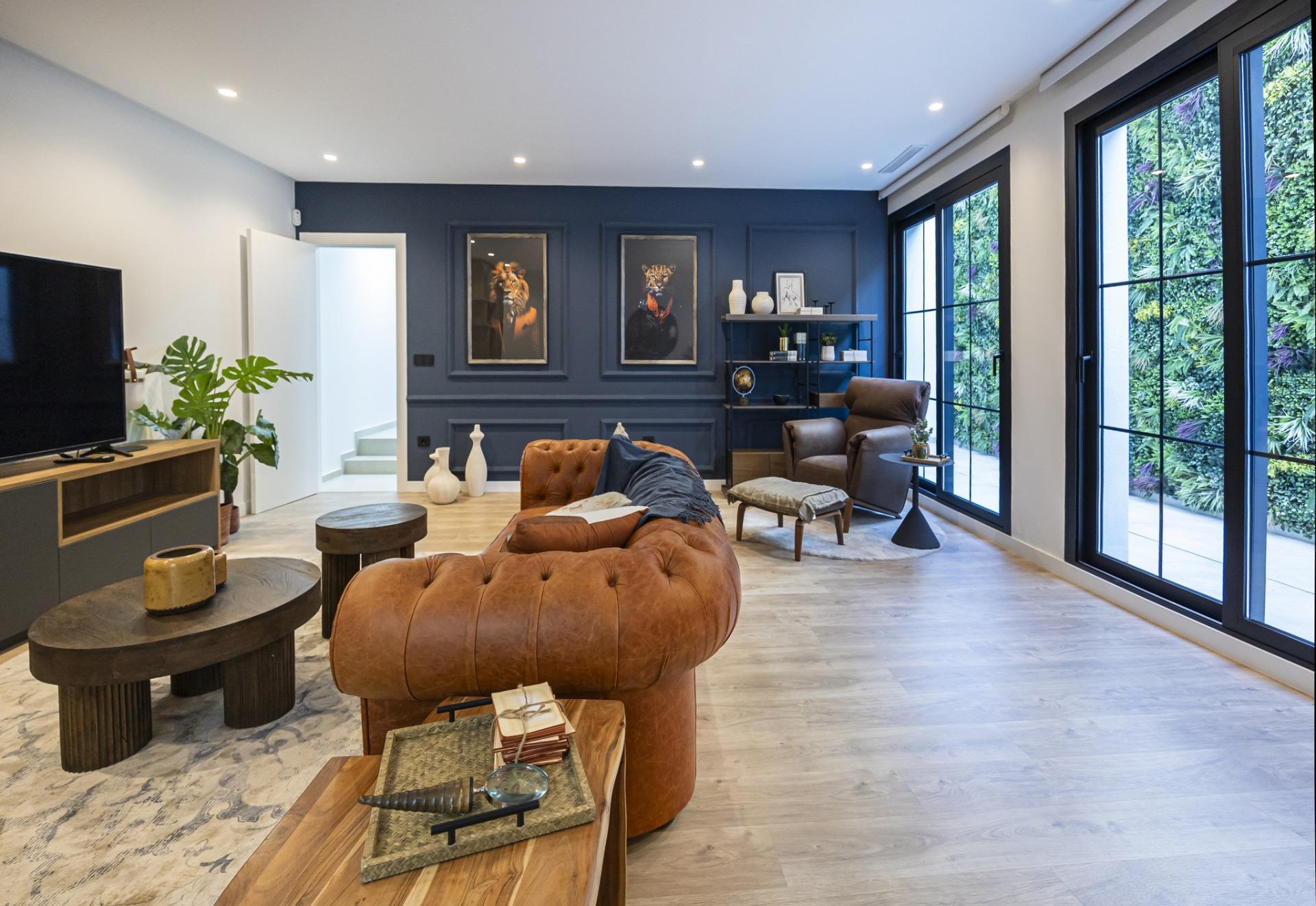 Spacious modern living room in bespoke 3-bedroom villa with leather sofa, artistic decor, and large black-framed windows...