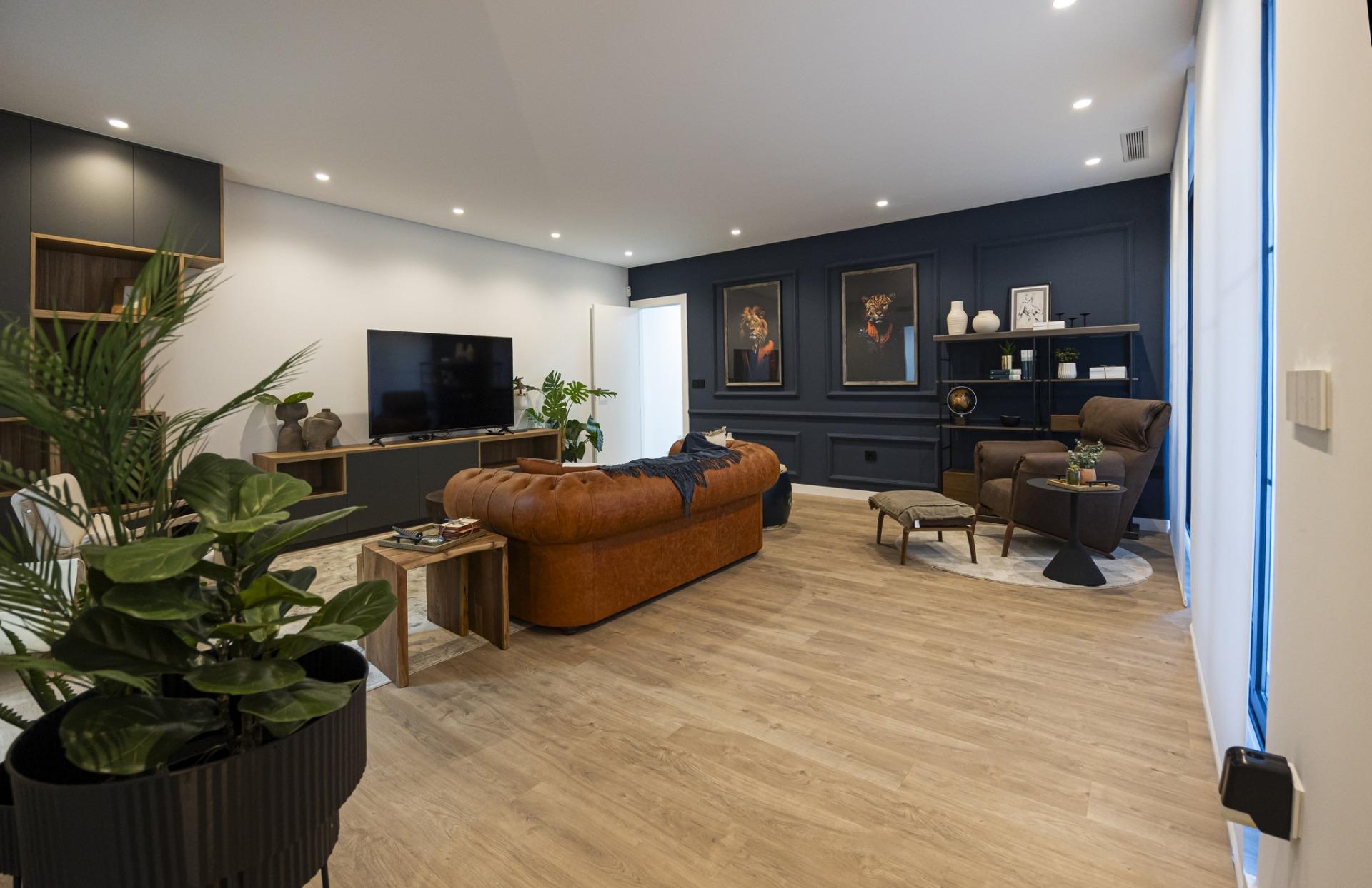 Spacious modern living room in bespoke 3-bedroom villa with leather sofa, dark accent wall, and natural wood flooring in...