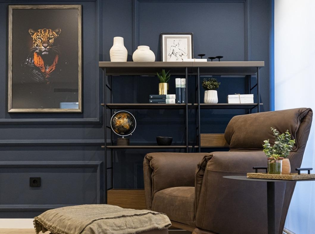 Cozy corner of bespoke Costa Blanca villa featuring a sleek brown leather armchair, ottoman, and elegant navy accent wall.
