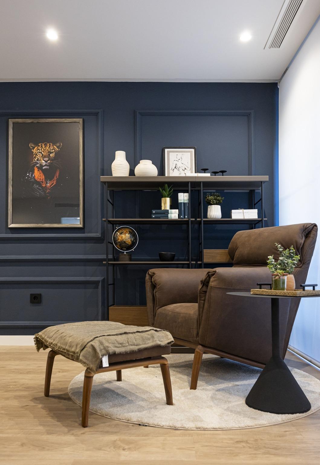 Cozy corner of bespoke Costa Blanca villa featuring a sleek brown leather armchair, ottoman, and elegant navy accent wall.