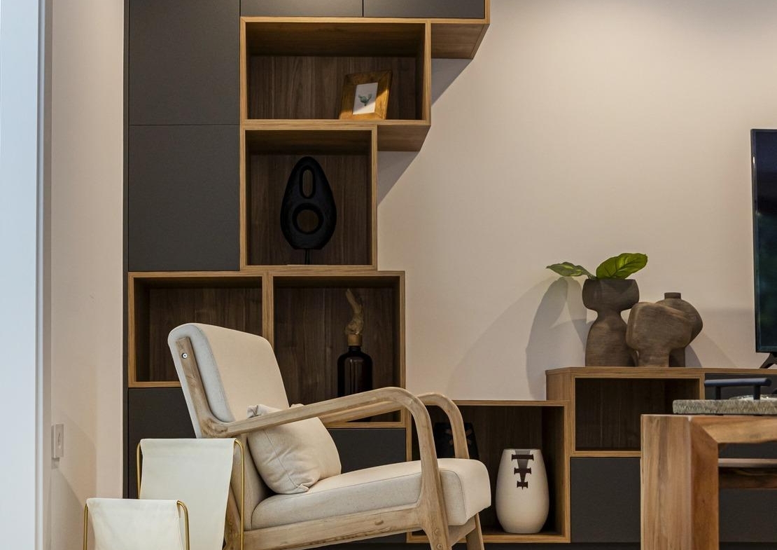 Bright and elegant living room corner in bespoke villa, featuring sleek wooden shelving, cream armchair, and decorative...