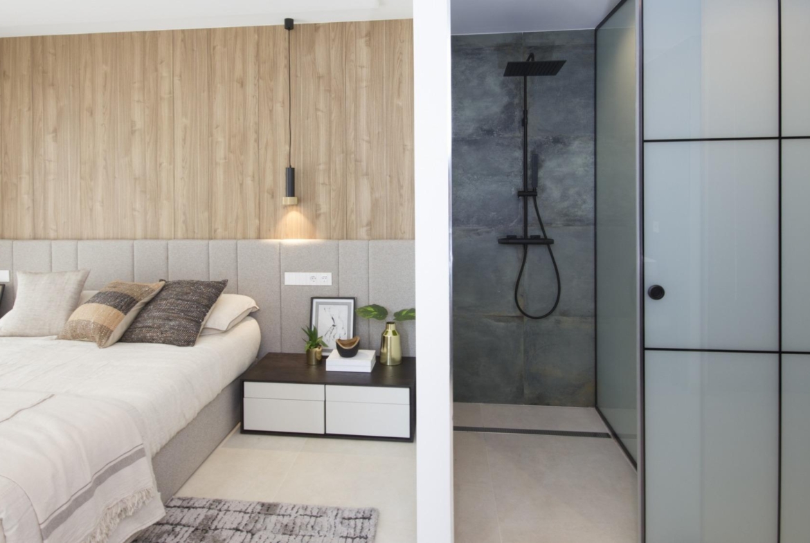 Bright modern bedroom with sleek beige bed, textured cushions, wood paneling, and stylish shower in bespoke villa in...