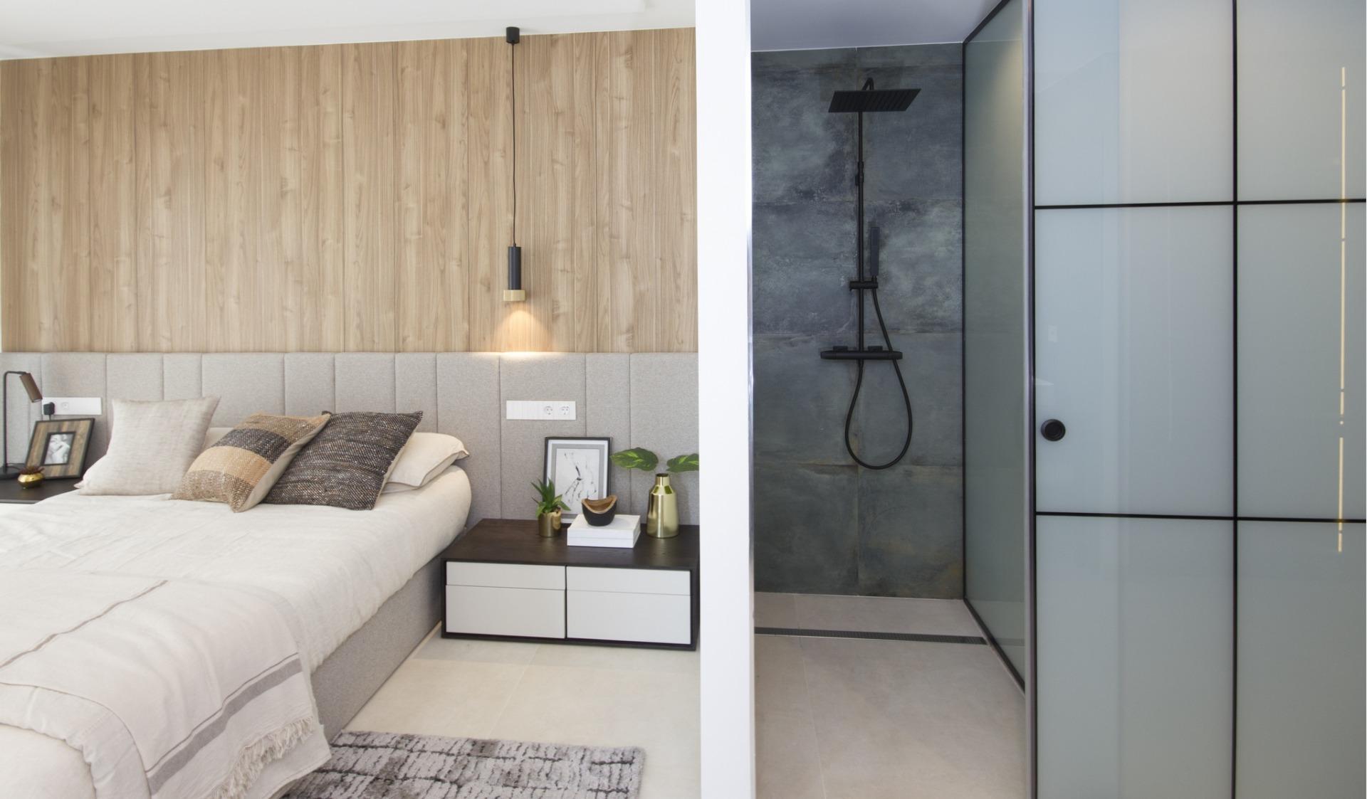 Bright modern bedroom with sleek beige bed, textured cushions, wood paneling, and stylish shower in bespoke villa in...