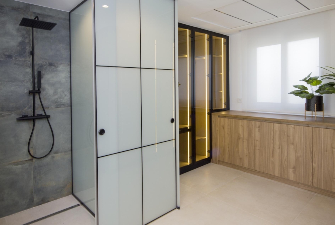 Modern bespoke villa bathroom in Ciudad Quesada featuring sleek black fixtures, illuminated glass cabinets, and natural...