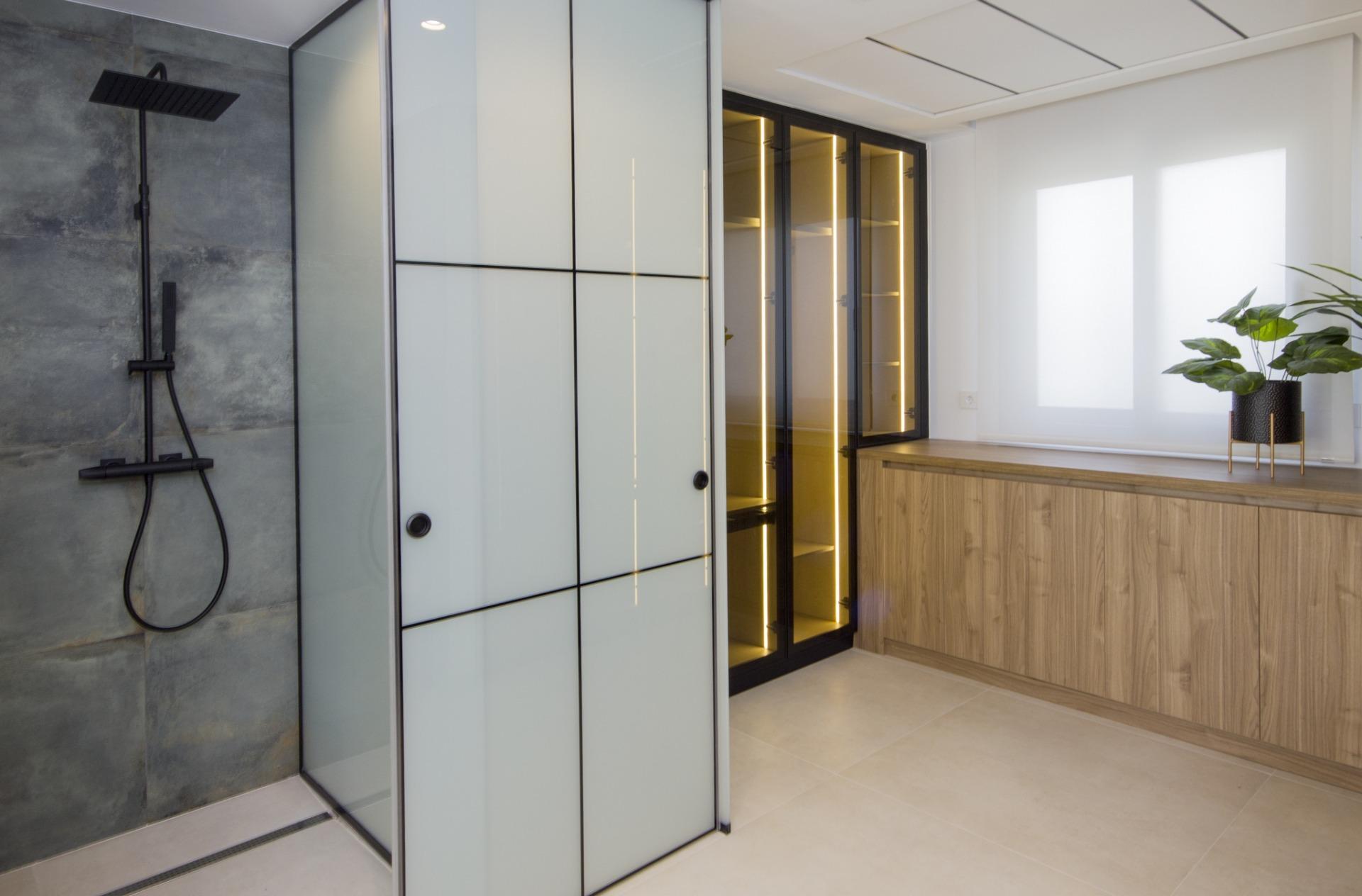 Modern bespoke villa bathroom in Ciudad Quesada featuring sleek black fixtures, illuminated glass cabinets, and natural...