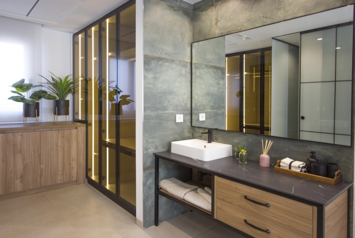 Modern bespoke villa bathroom in Ciudad Quesada with sleek wood cabinetry, illuminated glass wardrobes, and textured grey...