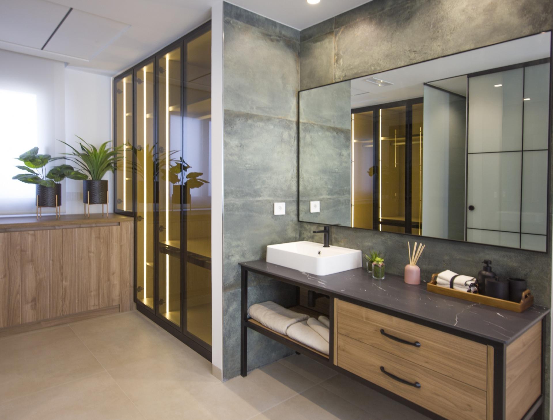 Modern bespoke villa bathroom in Ciudad Quesada with sleek wood cabinetry, illuminated glass wardrobes, and textured grey...