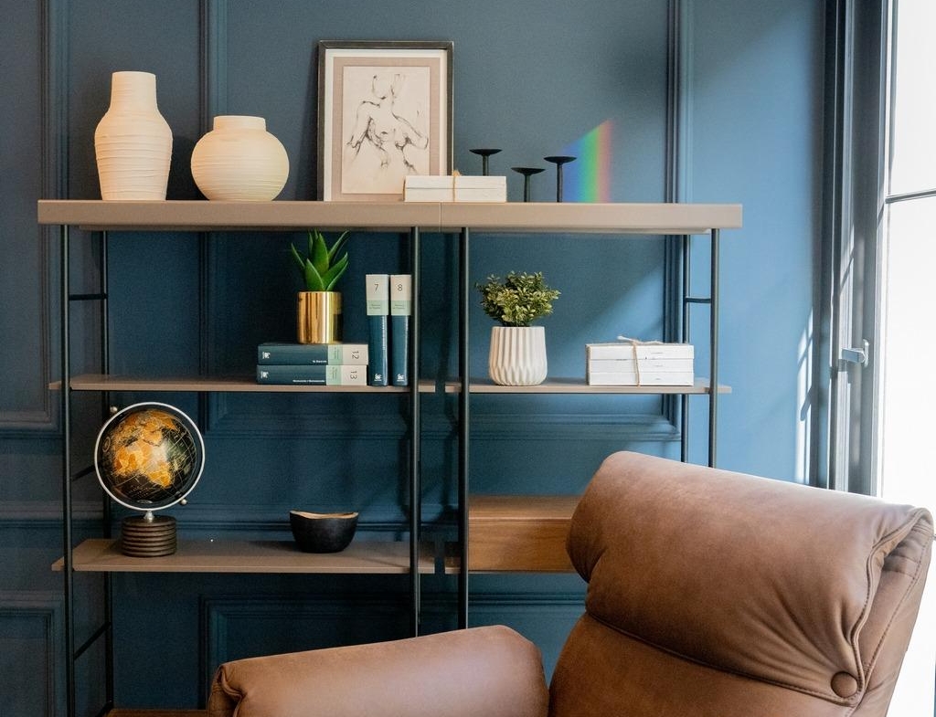 Cozy corner in a bespoke Costa Blanca villa featuring a rich blue wall, modern shelving, and a plush brown leather...