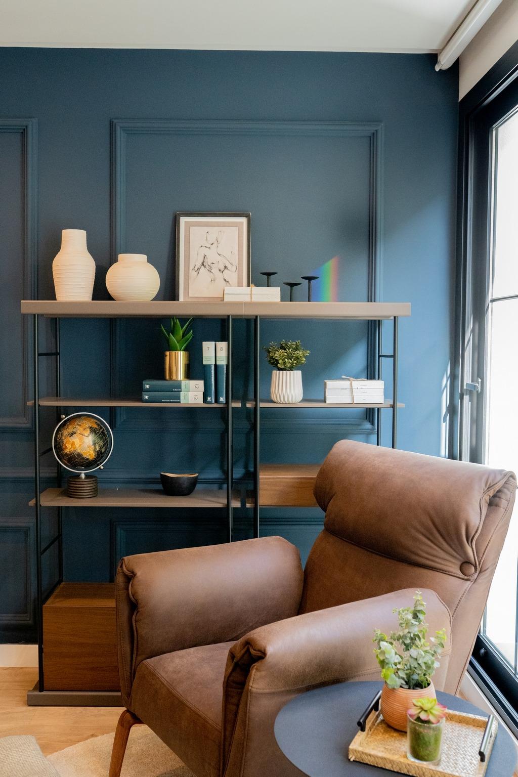 Cozy corner in a bespoke Costa Blanca villa featuring a rich blue wall, modern shelving, and a plush brown leather...