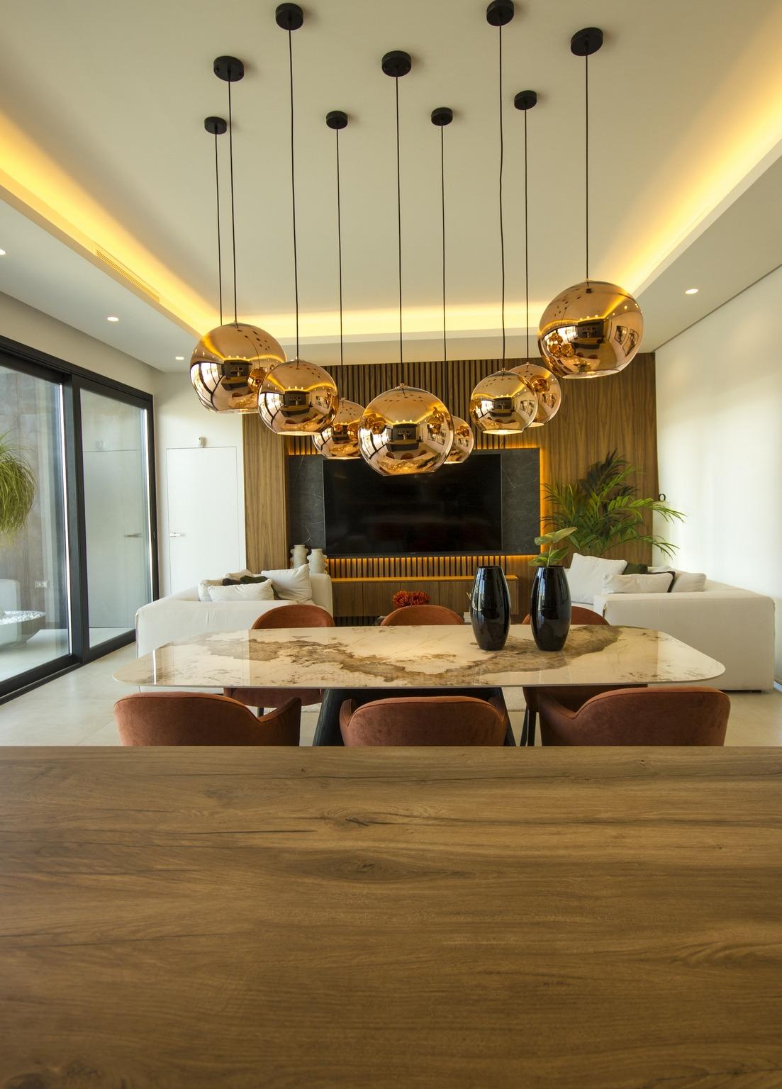 Modern bespoke 3-bedroom villa dining area in Ciudad Quesada with sleek marble table, copper pendant lights, and bright...