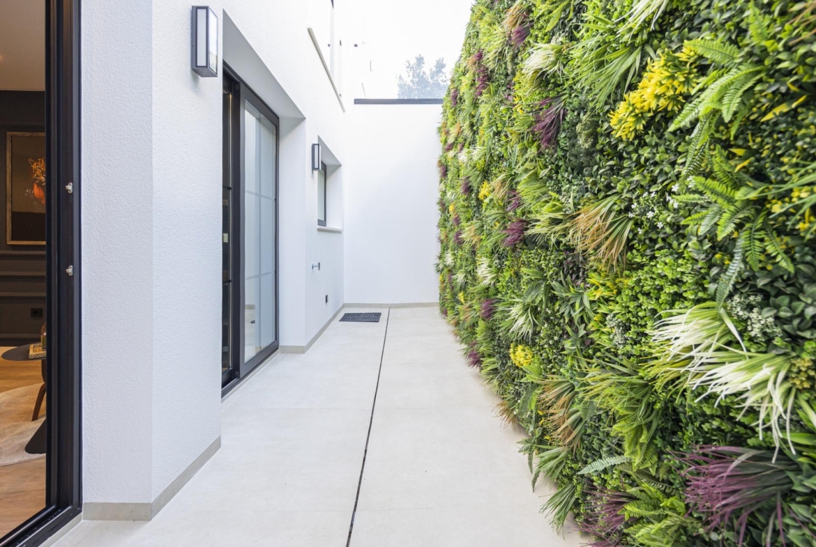 Bright modern villa corridor in Ciudad Quesada with sleek white walls and a vibrant vertical garden feature wall