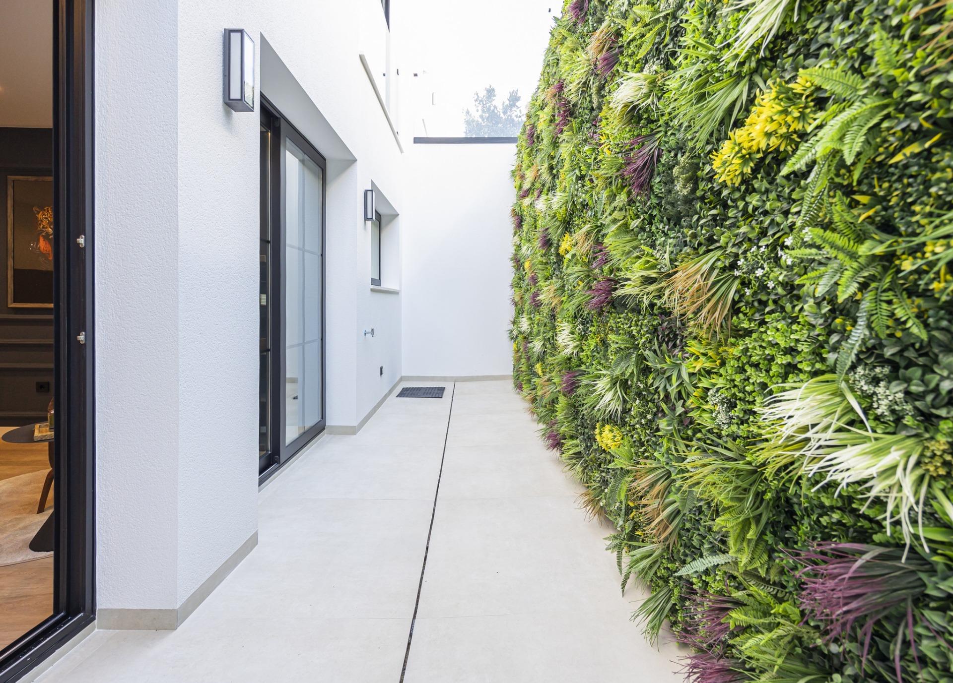 Bright modern villa corridor in Ciudad Quesada with sleek white walls and a vibrant vertical garden feature wall