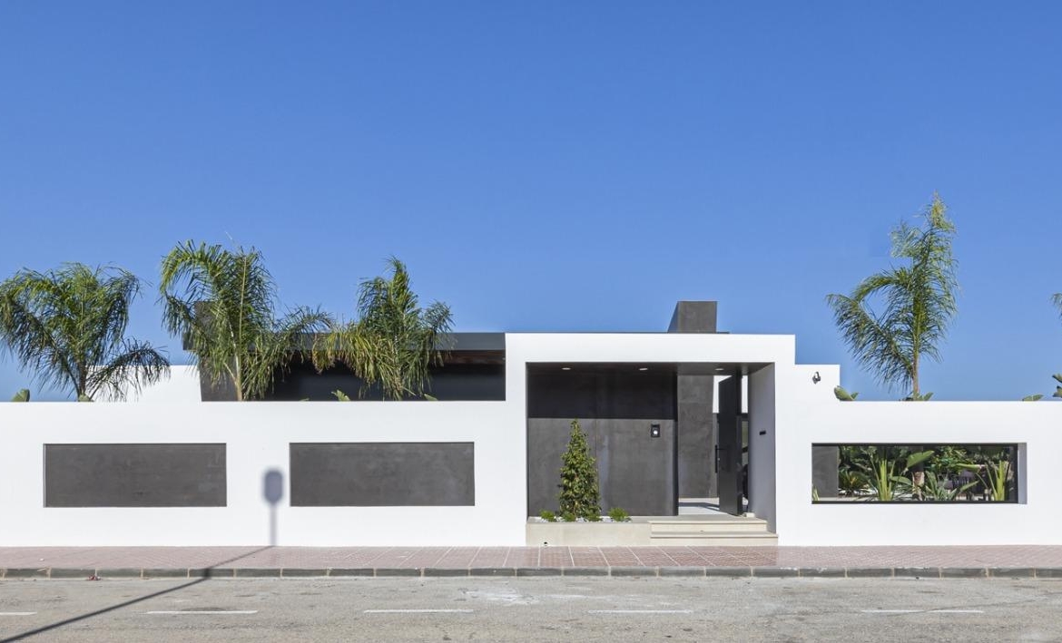 Sleek and modern bespoke 3-bedroom villa with clean white facade and lush palm trees in sunny Ciudad Quesada, Costa Blanca