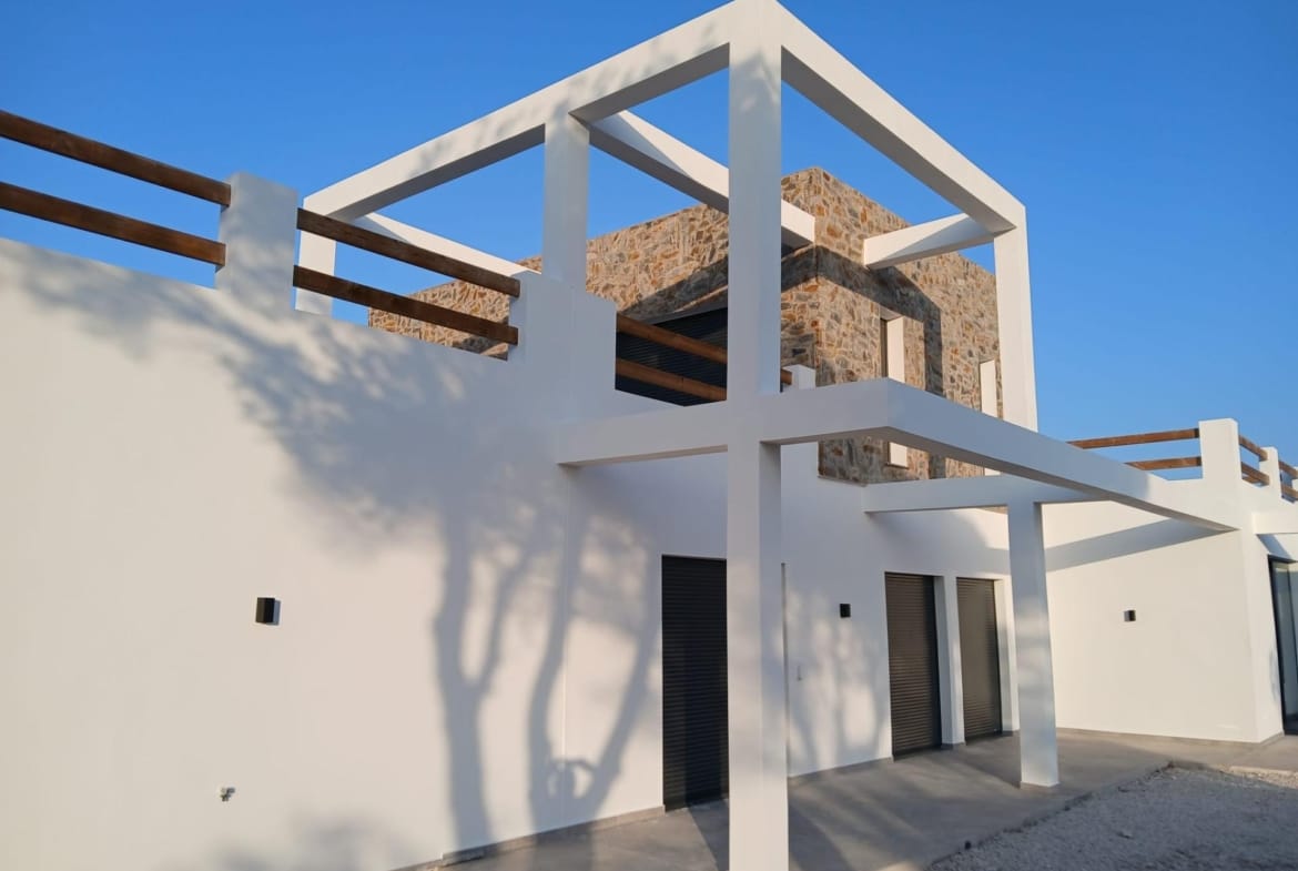 Two-storey villa facade with terrace beams and stone cladding in Pinoso, Alicante