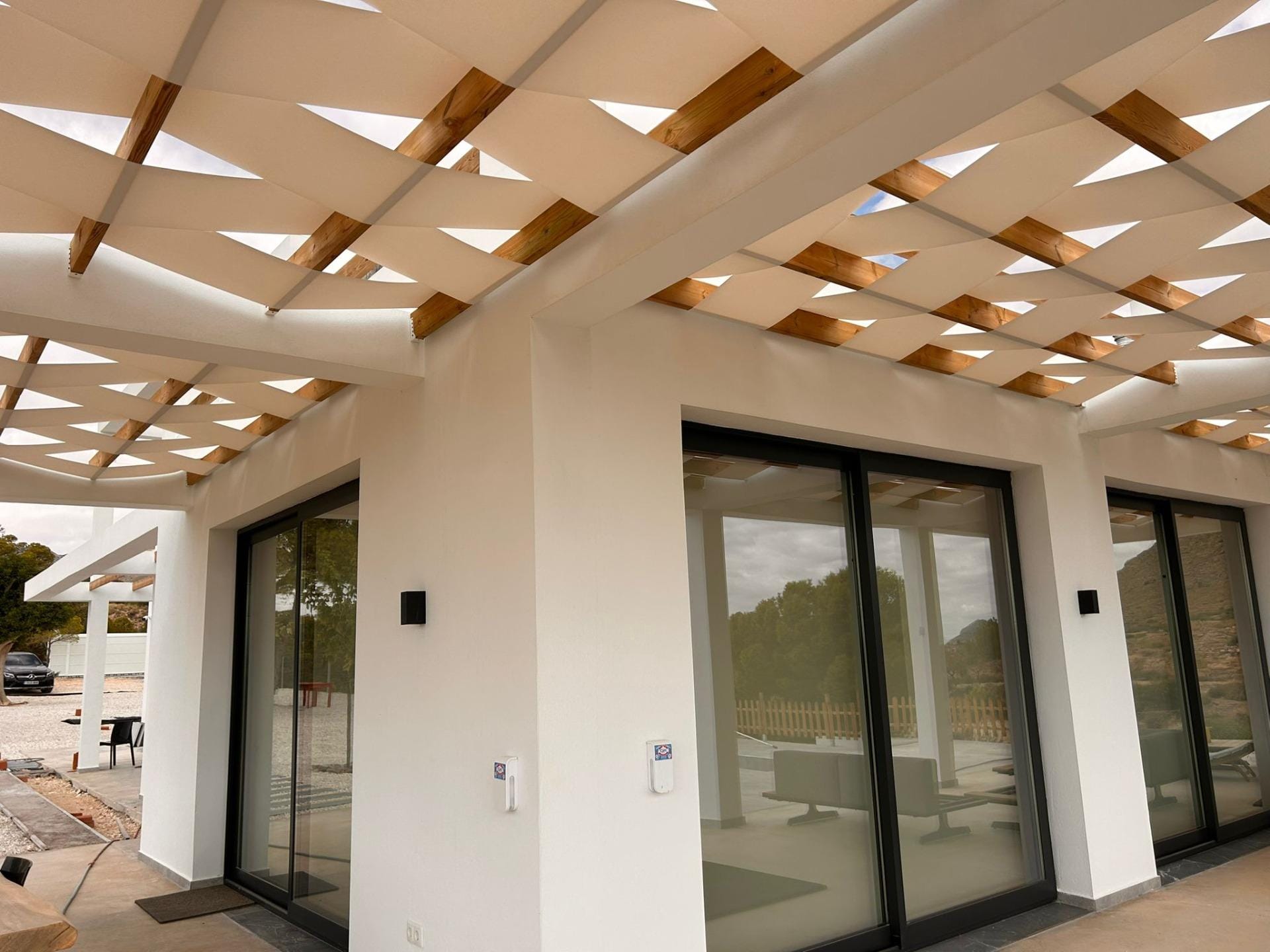 Custom-Built-New-Villas-in-Pinoso-Alicante-Spacious-Homes-in-Natural-Surroundings-12 Villa corner with sliding glass doors beneath terrace shade panels in Pinoso, Alicante