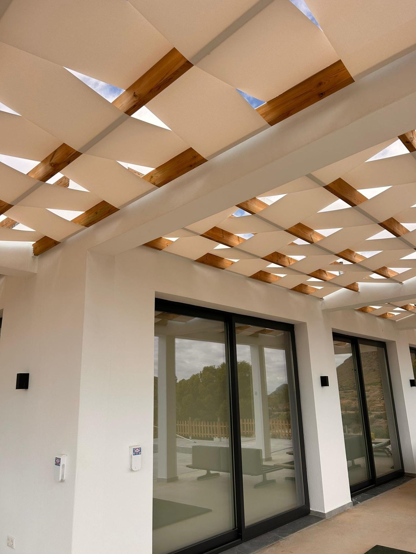 Custom-Built-New-Villas-in-Pinoso-Alicante-Spacious-Homes-in-Natural-Surroundings-13 Shaded terrace and sliding glass doors along a villa facade in Pinoso, Alicante