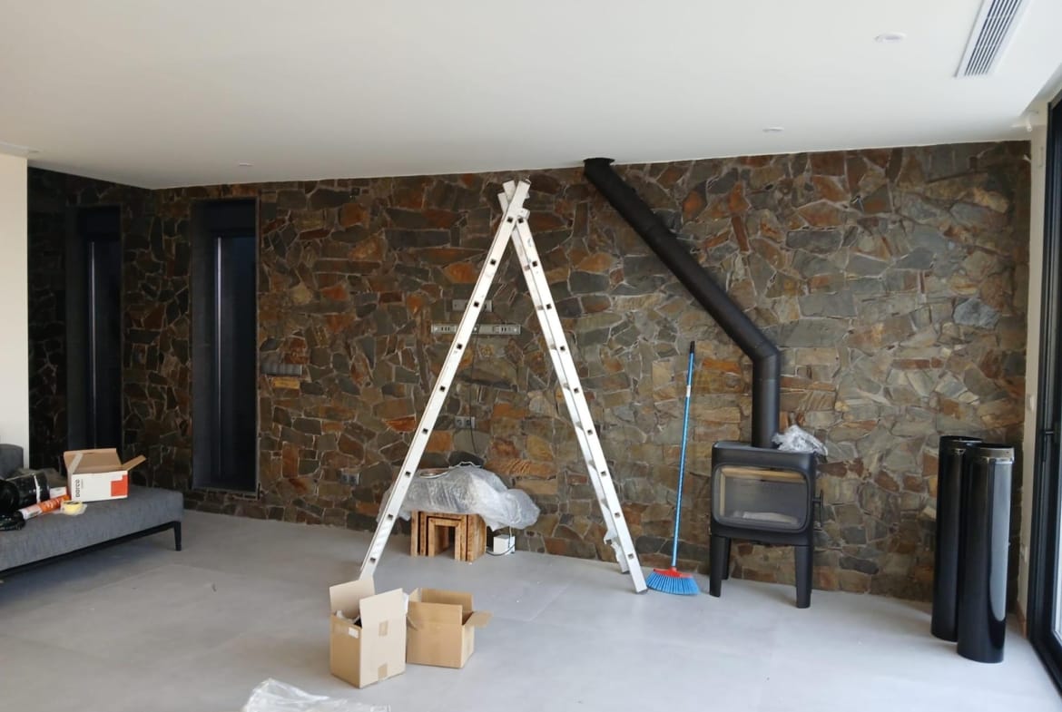 Living room during finishing work with a stone wall and wood stove in Pinoso, Alicante