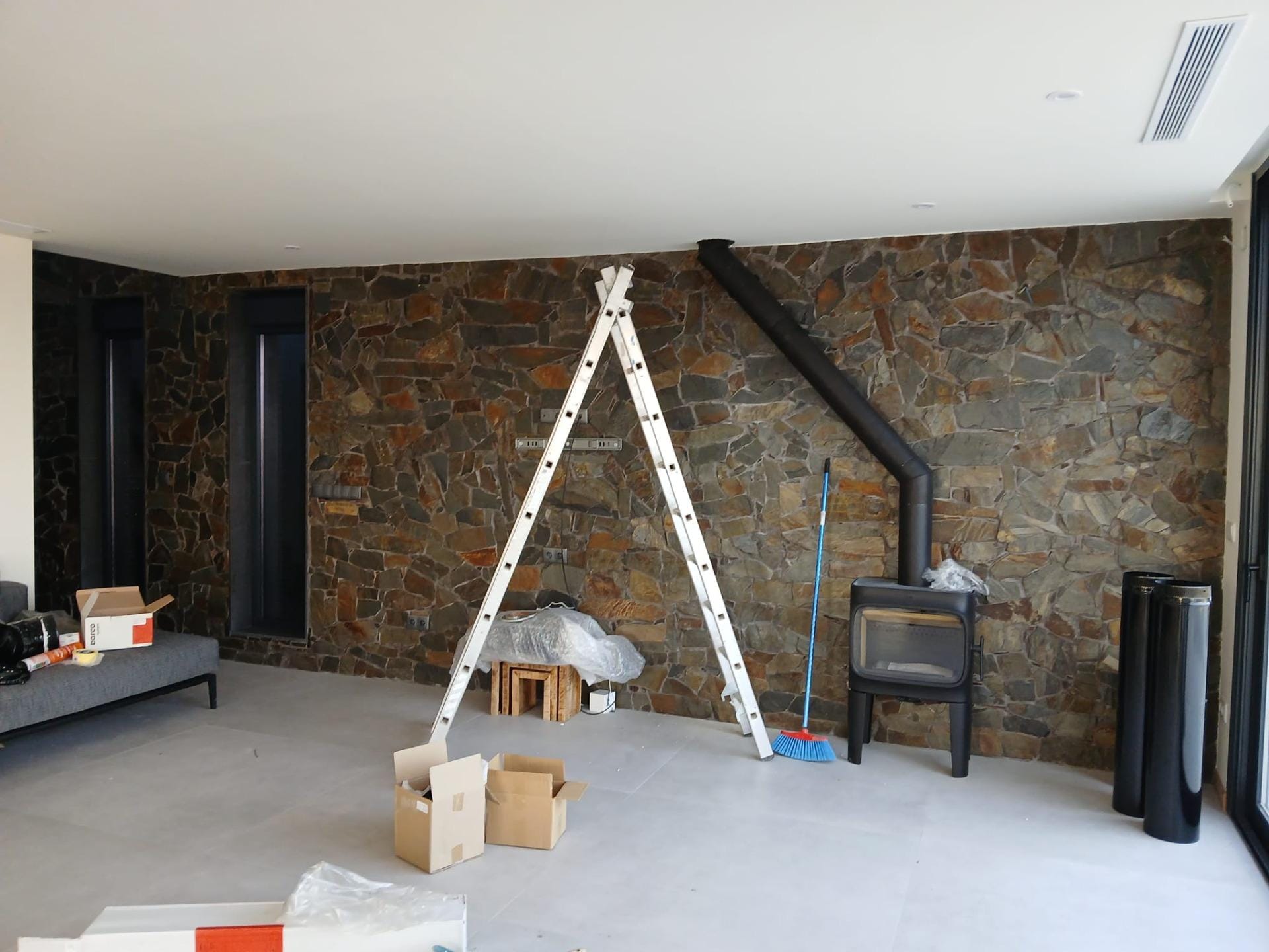 Custom-Built-New-Villas-in-Pinoso-Alicante-Spacious-Homes-in-Natural-Surroundings-14 Living room during finishing work with a stone wall and wood stove in Pinoso, Alicante