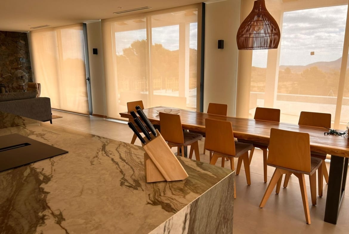 Kitchen island and dining table beside sunlit glass doors in Pinoso, Alicante