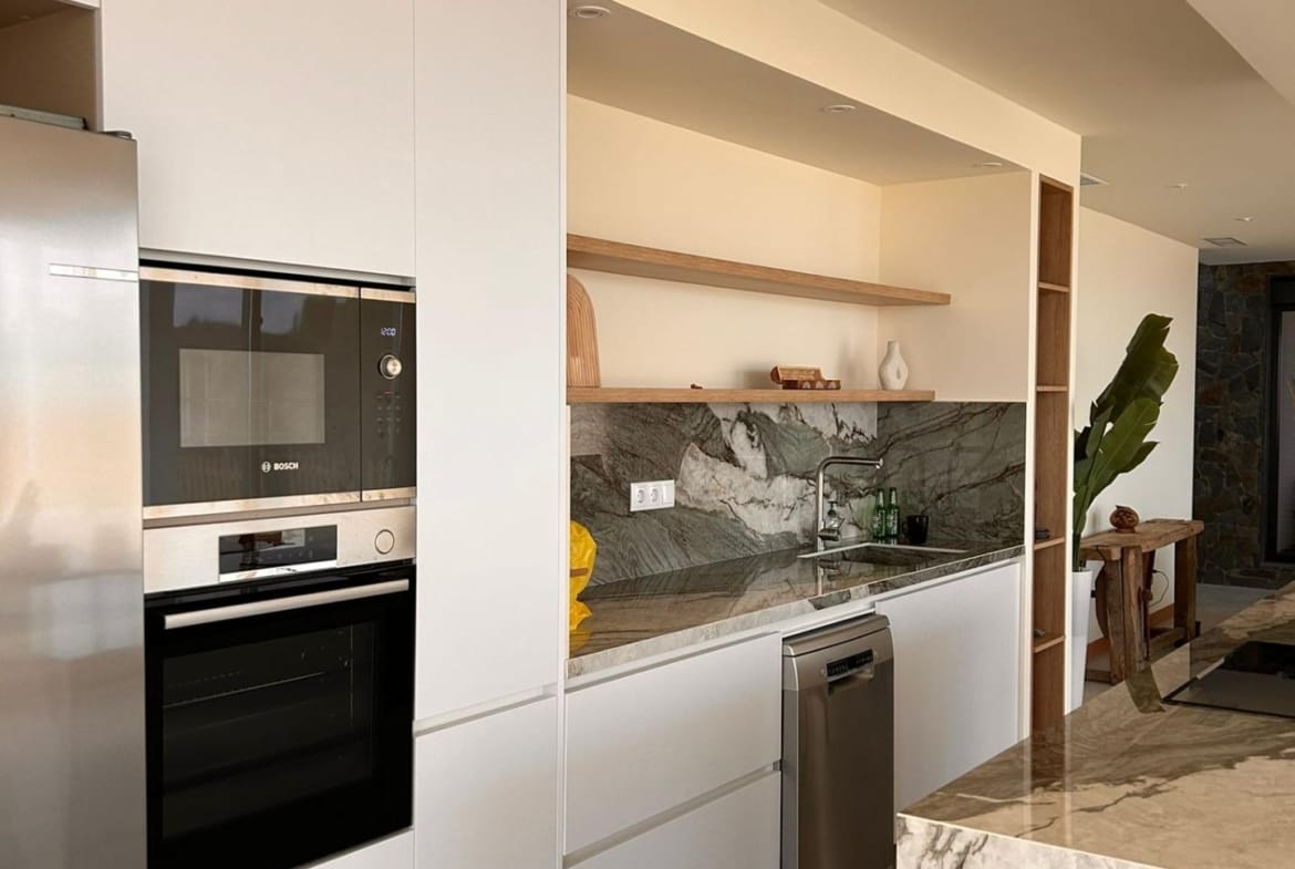 Fitted kitchen cabinets and worktop beside a stone-pattern island in Pinoso, Alicante