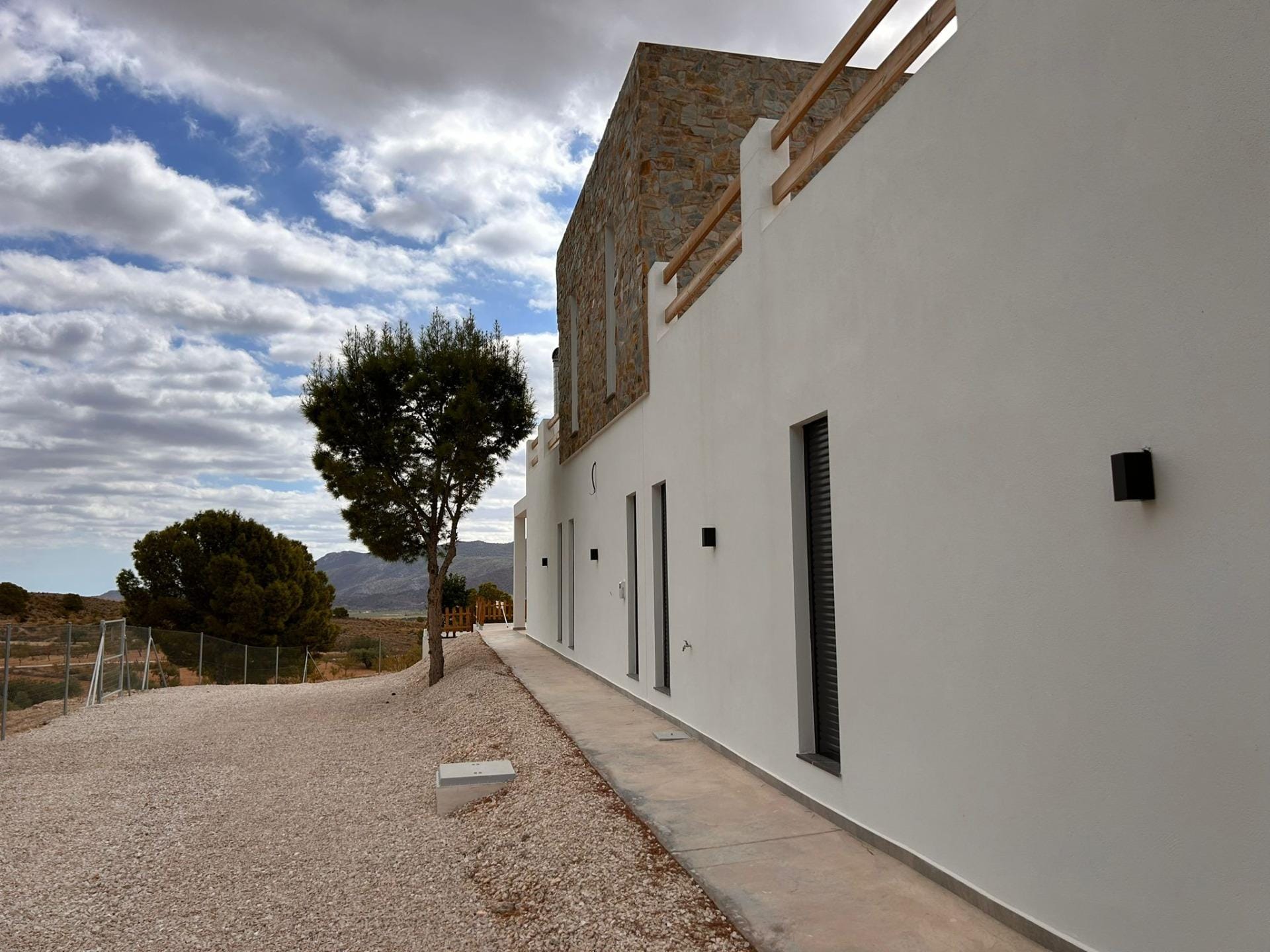 Custom-Built-New-Villas-in-Pinoso-Alicante-Spacious-Homes-in-Natural-Surroundings-24 Villa side facade, gravel garden and countryside setting in Pinoso, Alicante