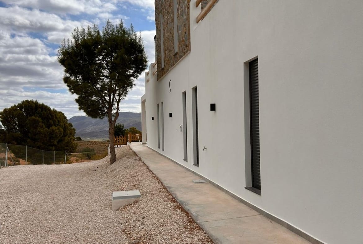 Side path along a white villa facade and gravel garden in Pinoso, Alicante